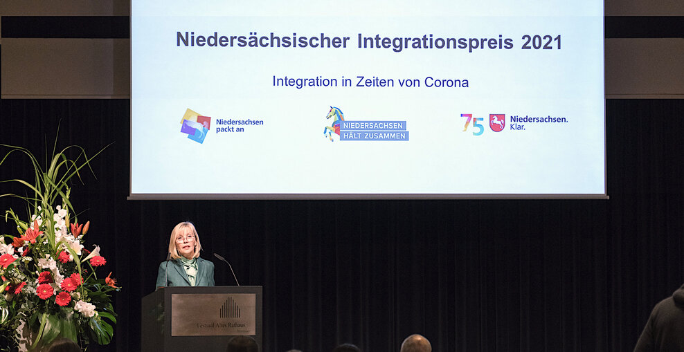 Die Landesbeauftragte für Migration und Teilhabe Doris Schröder-Köpf Doris Schröder-Köpf steht auf einer Bühne hinter einem Redepult