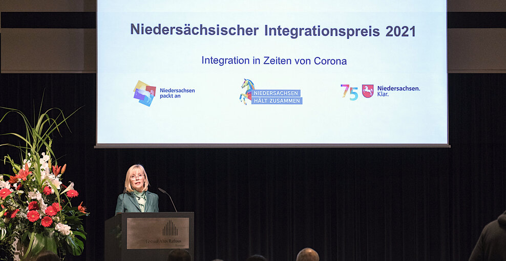 Die Landesbeauftragte für Migration und Teilhabe Doris Schröder-Köpf Doris Schröder-Köpf steht auf einer Bühne hinter einem Redepult